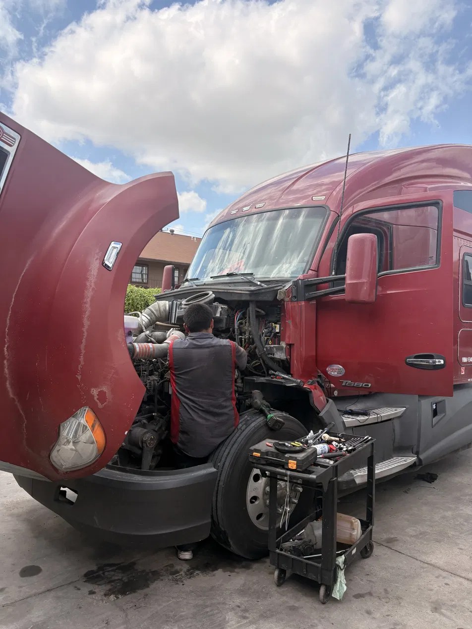 Technician working on red Kenworth engine at Techni Solutions